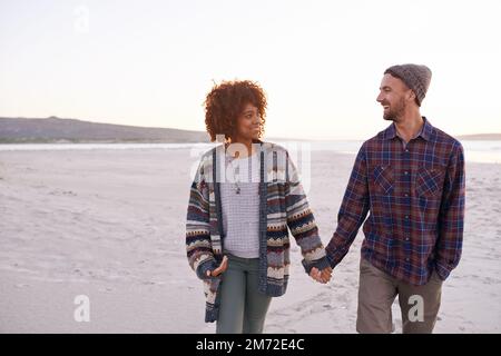 Lebe ohne Entschuldigungen, Liebe ohne Reue. Ein junges Paar, das einen Strandspaziergang genießt. Stockfoto