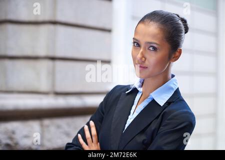Sie meint Geschäfte. Porträt einer selbstbewussten jungen Geschäftsfrau, die vor einem Gebäude steht. Stockfoto