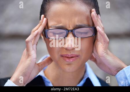 Zu viel zu tun. Eine junge Geschäftsfrau mit Kopfschmerzen. Stockfoto