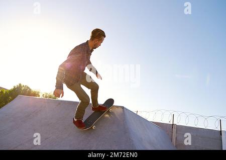 Ich besitze diese Rampen. Ein junger Mann, der auf seinem Skateboard im Skatepark Tricks macht. Stockfoto