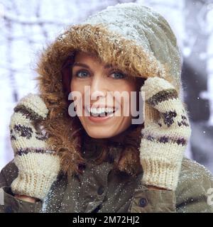 Liebe den ersten Schneefall. Eine attraktive Frau, die sich draußen im Schnee genießt. Stockfoto