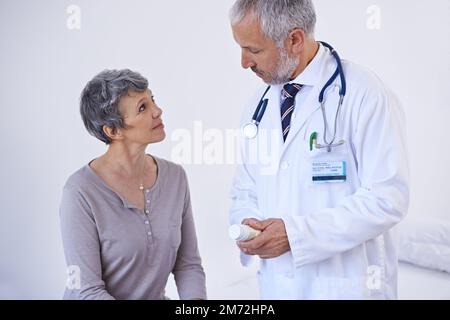 Folgen Sie diesen Anweisungen, um besser zu werden. Ein reifer Arzt, der einem Patienten Medikamente erklärt. Stockfoto