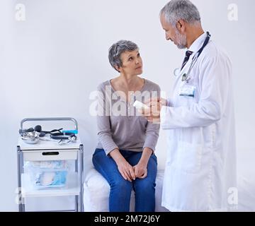 Die besten Medikamente auf dem Markt. Ein reifer Arzt, der einem Patienten Medikamente erklärt. Stockfoto