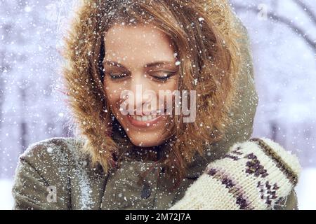 Liebe den ersten Schneefall. Eine attraktive Frau, die sich draußen im Schnee genießt. Stockfoto