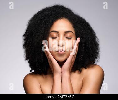 Gesichtskuss, Schönheits-Hautpflege und schwarze Frau mit geschlossenen Augen im Studio isoliert auf grauem Hintergrund. Make-up, Naturkosmetik und junges weibliches Modell Stockfoto