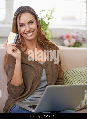 Ich muss nicht mal von zu Hause weg, um einkaufen zu gehen. Porträt einer attraktiven Frau, die mit ihrem Laptop sitzt und zu Hause online einkauft. Stockfoto