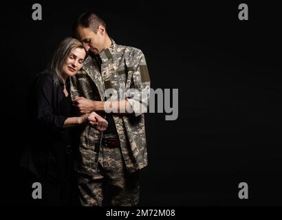Glückliche Frau sein Mann umarmen kam zurück von der Armee. Lächelnd heiteres kaukasischen Freundin ein Soldat. Stockfoto