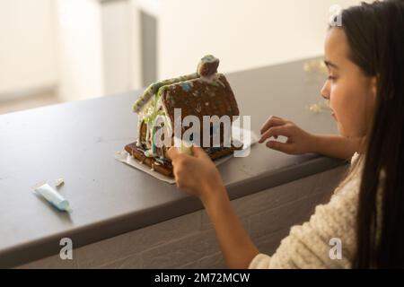 Ein Mädchen spielt mit einem Lebkuchenhaus für traditionelle Weihnachtsdekoration Stockfoto