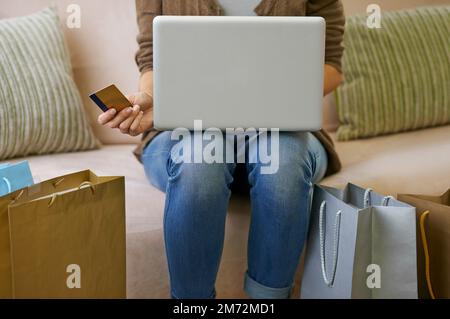 Online einkaufen ist so bequem. Eine Frau, die mit ihrem Laptop zu Hause online einkauft. Stockfoto