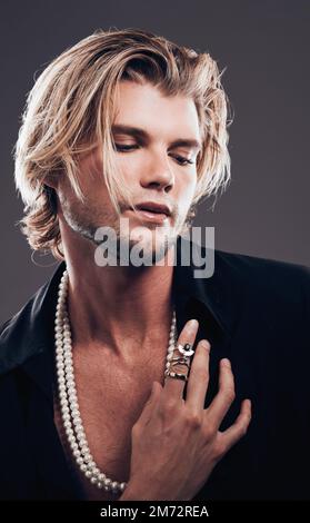 Schönheit, Mode und Accessoires mit einem männlichen Model im Studio auf grauem Hintergrund für transsexuelle Gleichheit. Geschlechtsneutral, nicht binär und Stil mit einem Stockfoto