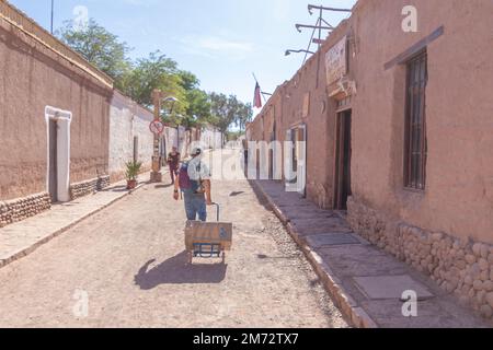 Ein Mann, der auf der gepflasterten Hauptstraße von San Pedro de Atacama spaziert, die einzige Oase in der Wüste Atacama, die trockenste Zone des Planeten Stockfoto