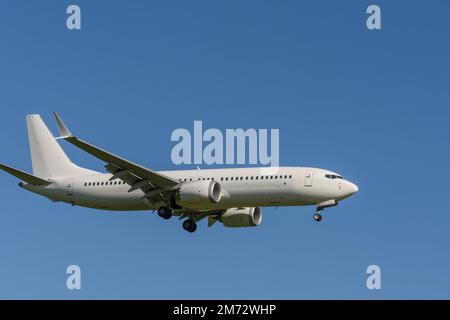 Weißes Passagierflugzeug gegen blauen Himmel kurz vor der Landung am Flughafen Stockfoto