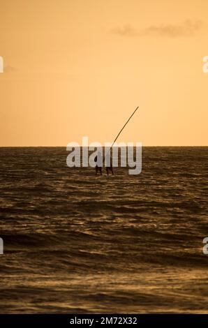 Zwei Fischer, die im Morgengrauen auf einem Floß arbeiten. Stockfoto