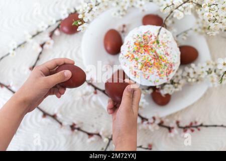 Rote Eier zu Ostern, traditionelles Ostermenü, Hände mit bemalten Eiern Stockfoto