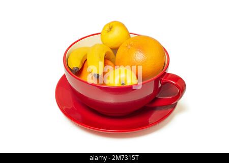 Früchte in einer riesigen, roten Teetasse, isoliert auf weißem Hintergrund Stockfoto