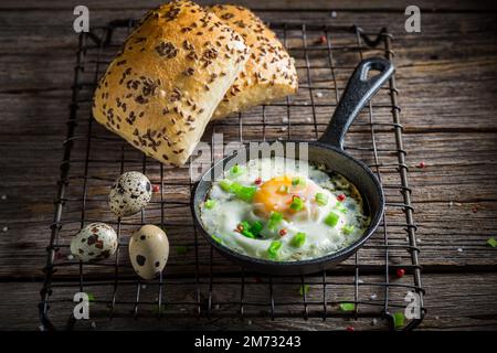 Hausgemachte und warme Spiegeleier mit Schnittlauch und Brötchen. Spiegeleier zum Frühstück. Stockfoto