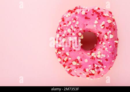 Rosafarbener Donut mit Streuseln auf pinkfarbenem Pastellhintergrund. Ein süßer rosa Donut. Draufsicht. Speicherplatz kopieren Stockfoto