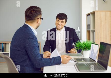 Zwei Kollegen im Büro sprechen über ein neues Projekt oder eine neue Aufgabe und tauschen Informationen aus. Stockfoto