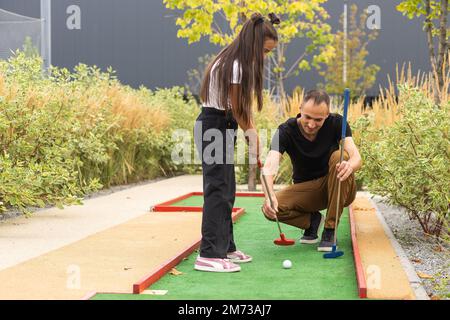 Vater und Tochter spielen gemeinsam im Park Minigolf Stockfoto