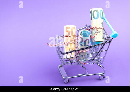 Ein Einkaufswagen voller rollender Euro-Banknoten. Stockfoto