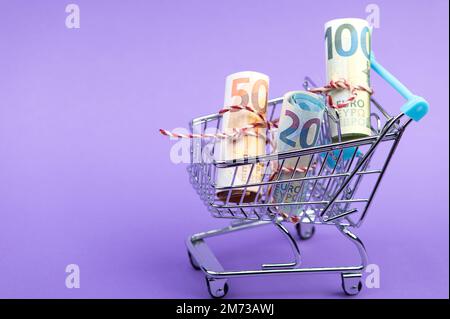 Ein Einkaufswagen voller rollender Euro-Banknoten. Stockfoto