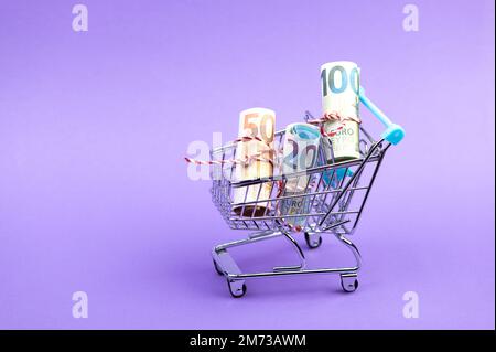 Ein Einkaufswagen voller rollender Euro-Banknoten. Stockfoto