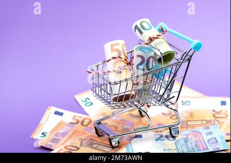 Ein Einkaufswagen voller rollender Euro-Banknoten. Stockfoto