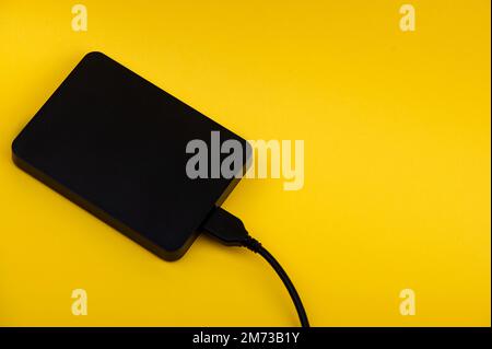 Schwarze externe tragbare Festplatten isoliert auf gelbem Hintergrund Stockfoto