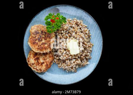 Buchweizen mit Fleischschnitzeln auf schwarzem Hintergrund, Draufsicht Stockfoto