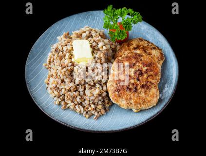 Buchweizen mit Fleischschnitzeln auf schwarzem Hintergrund, Draufsicht Stockfoto