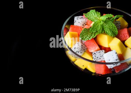 Obstsalat aus ostasiatischen Früchten, isoliert auf schwarzem Hintergrund, Seitenansicht Stockfoto