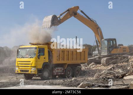 Ein Bagger, der auf einer Baustelle Schutt in einen Muldenkipper lädt Stockfoto