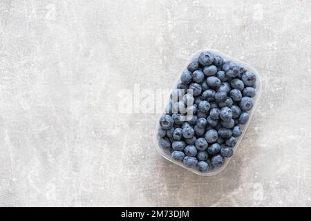 Frische Blaubeere in einer Kunststoffbox auf weißem Hintergrund. Platz für Text. Stockfoto