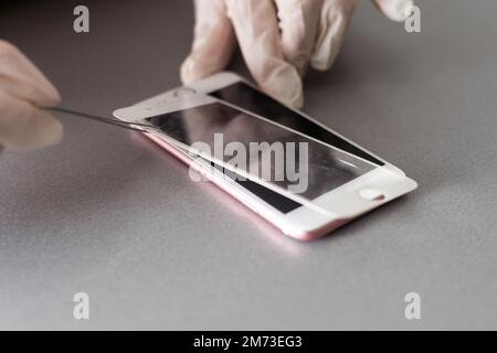 Smart Solution Technologiekonzept. Zugeschnittener Fotoersatz von Schutzfolie durch einen neuen. Man entfernt vorsichtig das alte Schutzglas aus dem Stockfoto