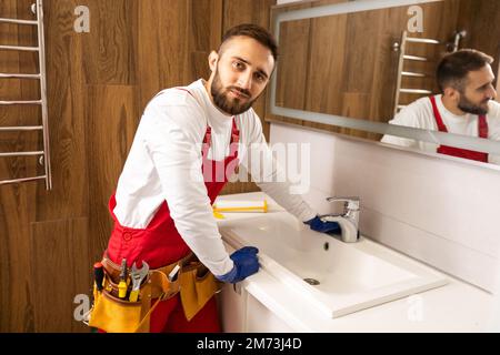 Professioneller Klempner mit Kolben und Instrumenten in der Nähe des Waschbeckens. Stockfoto