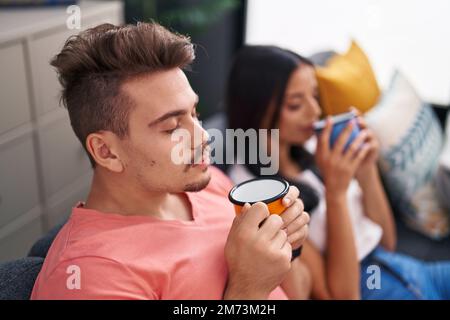Mann und Frau, ein lächelndes Paar, das zu Hause auf dem Sofa sitzt Stockfoto