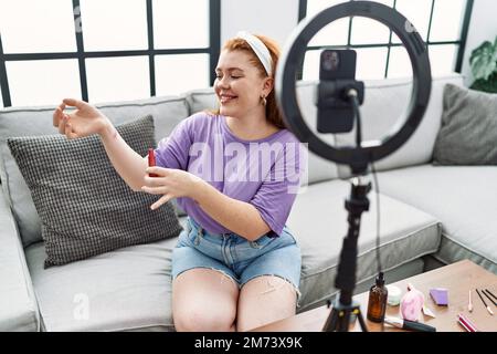 Junge Rotschopf Frau Make-up-Tutorial mit Smartphone zu Hause Stockfoto