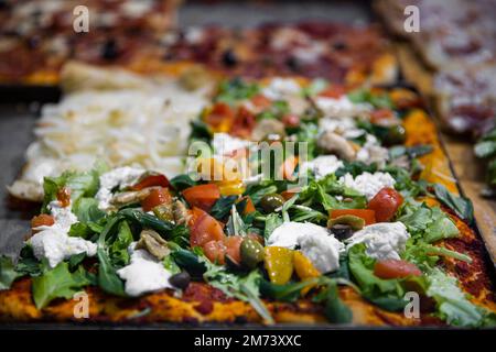 Street Food Pizza in Naples, Italia. Verschiedene Pizzasorten, mit Schinken, Gemüse und Käse, Draufsicht. Stockfoto