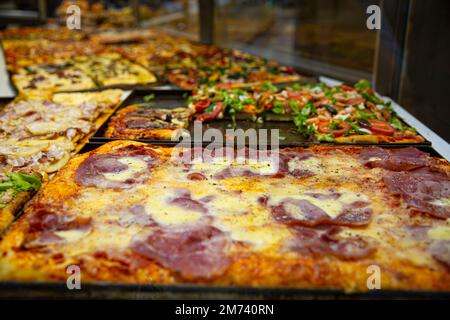 Street Food Pizza in Naples, Italia. Verschiedene Pizzasorten, mit Schinken, Gemüse und Käse, Draufsicht. Stockfoto