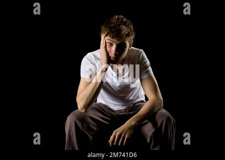 Porträt eines sitzenden, emotional aussehenden 17-jährigen Teenagers Stockfoto