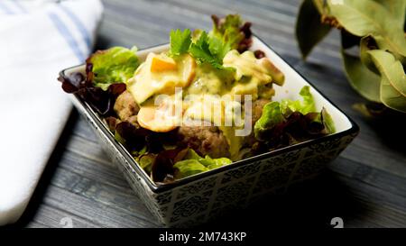 Fleischbällchen mit Currysauce und Salat. Stockfoto