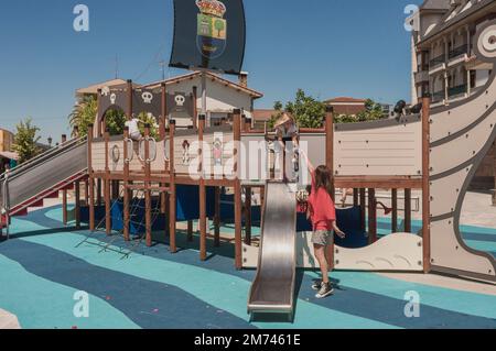 Mutter gibt ihrer Tochter eine Flasche Wasser auf einem hölzernen Kletterboot auf einem öffentlichen Spielplatz im Dorf Colindres, Kantabrien, Spanien, Europa Stockfoto