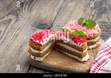 Hausgemachtes Dessert mit Schlagsahne und herzförmigen Streuseln auf einem Holztisch Stockfoto