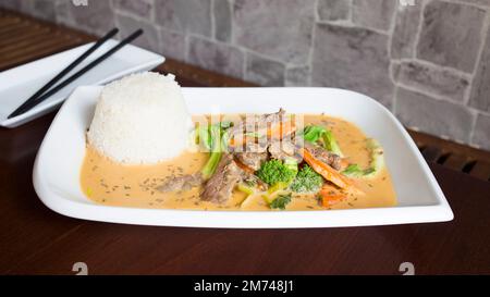 Asiatische Kombi-Platte mit Rindfleisch in Currysauce und Gemüse serviert mit Reis. Stockfoto