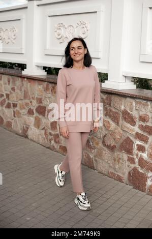 Ein dunkelhaariges Mädchen läuft durch die Stadt und posiert in einem türkisfarbenen Kleid Stockfoto