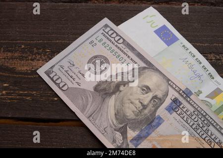 Ein Hundert-Dollar-Schein und 100-Euro-Schein, Hintergrund von 100-Dollar- und 100-Euro-Schein-Banknoten. Banknoten auf Holzoberflächen. Tapetengeschäft und Fi Stockfoto