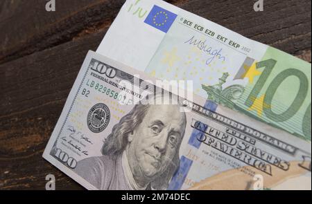 Ein Hundert-Dollar-Schein und 100-Euro-Schein, Hintergrund von 100-Dollar- und 100-Euro-Schein-Banknoten. Banknoten auf Holzoberflächen. Tapetengeschäft und Fi Stockfoto