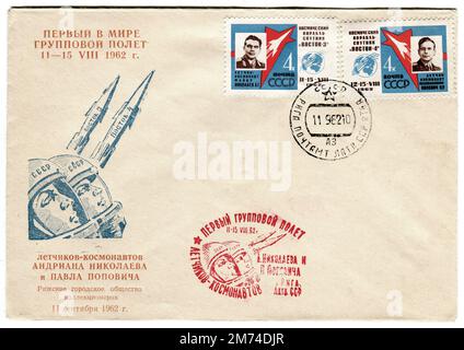 Eine alte russische Weltraumhülle, die am 11. September 1962 veröffentlicht wurde, um den Flügen von Vostok 3 und Vostok 4 zu gedenken. Das Cover ist mit einem stilisierten Bild der beiden Raketen, ihrer Kosmonauten-Piloten und der dazugehörigen übersetzten Überschrift „First in the World Group Flight 11-15 August 1962“ und „Cosmonauts Andriana Nikolaev und Paul Popovich – Riga City Society Collectors – 11. September 1962“ dekoriert. Vostok 4 war eine sowjetische Raumfahrtmission, die im August 1962 gestartet wurde, einen Tag nach Vostok 3; das erste Mal, dass mehr als ein besetztes Raumschiff gleichzeitig im Orbit war. Stockfoto