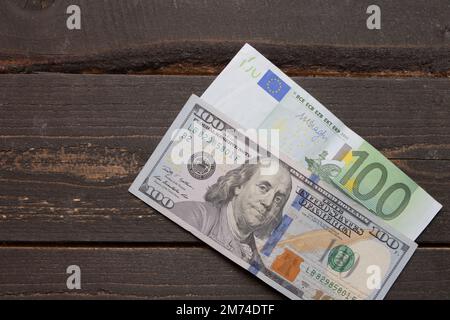 Ein Hundert-Dollar-Schein und 100-Euro-Schein, Hintergrund von 100-Dollar- und 100-Euro-Schein-Banknoten. Banknoten auf Holzoberflächen. Tapetengeschäft und Fi Stockfoto