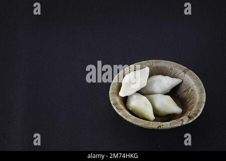 makar sangkranti oder edle sangkranti-Feier mit Puli Pithe oder bengalischem Reismehl Teigtaschen mit Kokosnussfüllungen, serviert auf einem Teller aus Schal pa Stockfoto